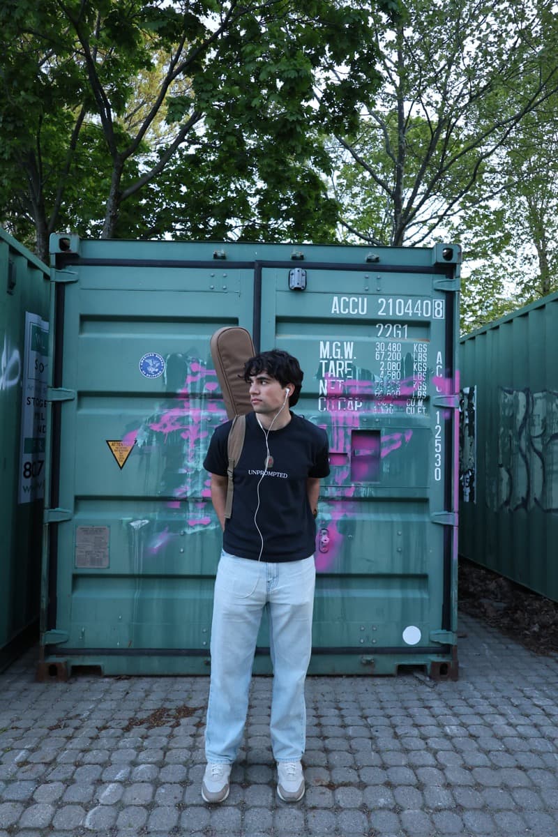 A musician standing beside a painted shipping container