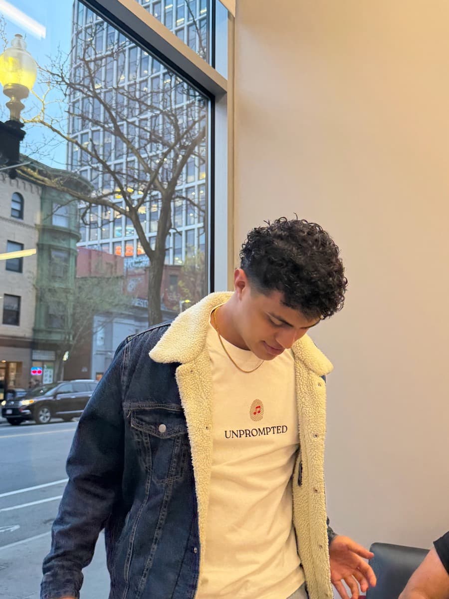 A musician in an Unprompted shirt by a window